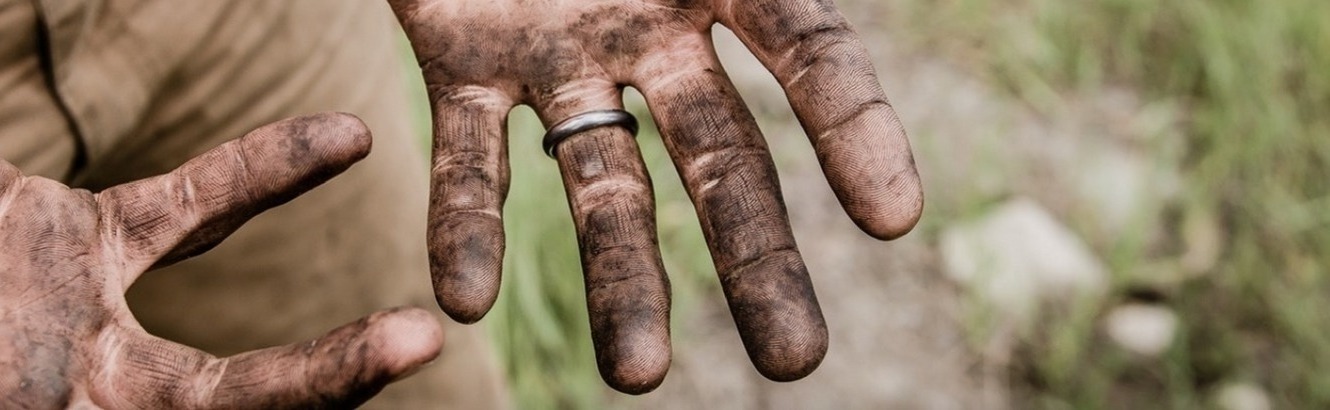 A man's hands covered with dirt.