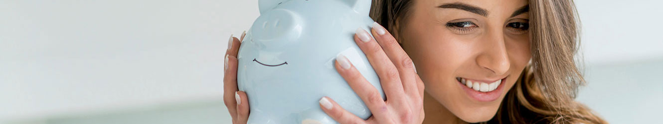 Young woman shaking piggy bank.