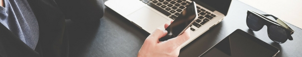 Person using a cell phone and a laptop computer.
