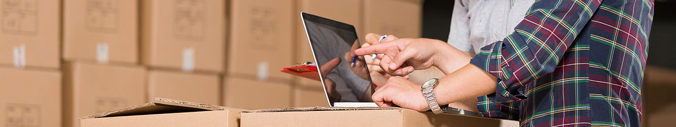 Two men working on computer in warehouse.