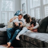 Mom and dad playing with two kids on the couch