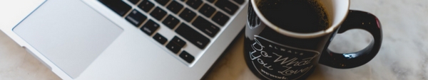 Computer sitting next to a cup of coffee.