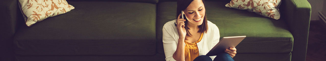 Young lady in living room using phone and tablet.