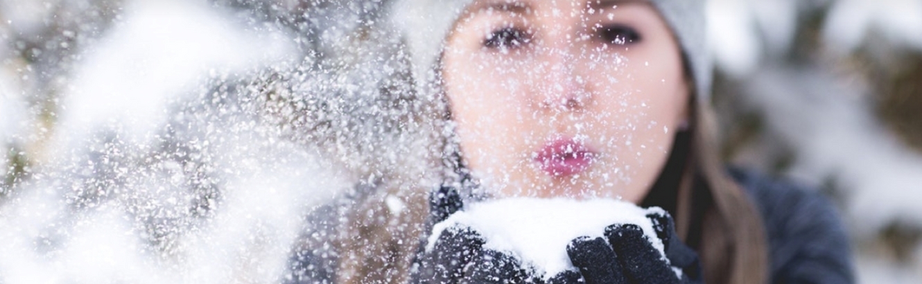Woman blowing snow out of her hands.