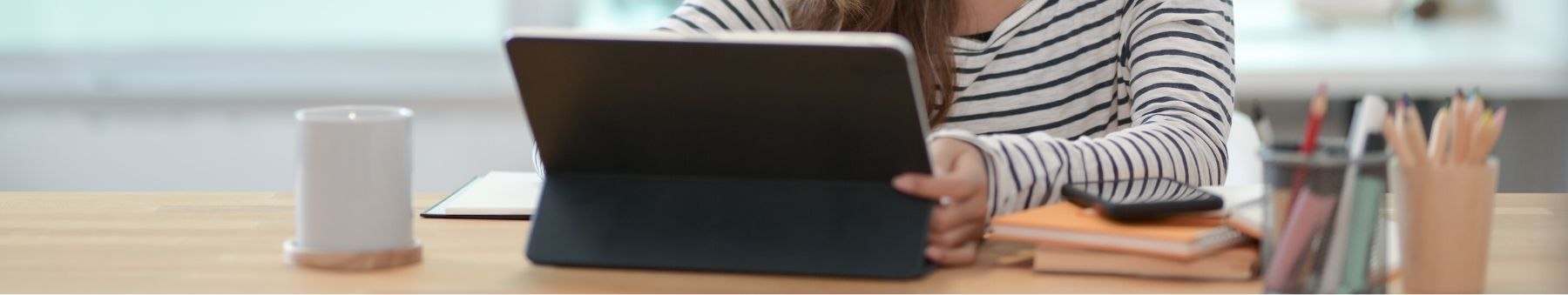 Woman using her tablet and a cell phone sitting on her desk